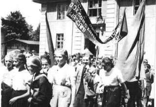 1950 rok. Święto Pracy. Uczniowie szkoły podstawowej w Mysłakowicach. Obok budynek starej (poniemieckiej) szkoły. 